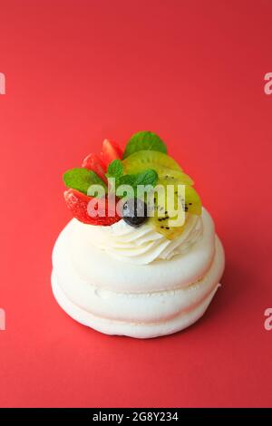 Mini Pavlova Cake meringa dessert con crosta croccante e morbido interno. Dolce meringa torta Pavlova con fragole fresche, kiwi e menta. Estate dess Foto Stock