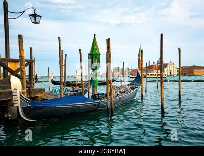 Splendida vista della tradizionale gondola veneziana ormeggiata dal molo e galleggiante sulle acque del Canal Grande a Venezia, Italia. Attrazione turistica, destinazione Foto Stock