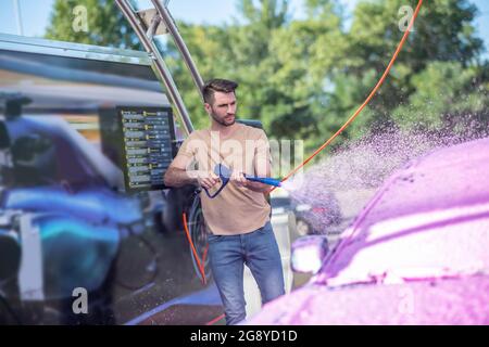 Servizio auto operaio lavando auto all'aperto Foto Stock