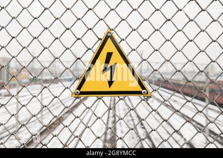 Segnale di pericolo di alta tensione sulla recinzione sopra la ferrovia. Foto Stock