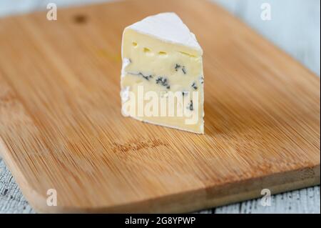 Incuneamento di formaggio blu sotto una crosta di muffa bianca Foto Stock