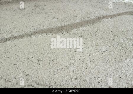 Cemento liquido ad un luogo di costruzione. Il cemento si è versato sulla strada. Il materiale da costruzione è cemento e ghiaia. Foto Stock