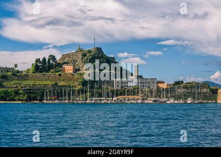 Isola di Corfù/Grecia- 7 maggio 2019: Paesaggio urbano di Kerkyra - baia di mare con acque turchesi calme, antica fortezza veneziana in pietra, vecchie case storiche Foto Stock