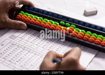fuoco selettivo sulla mano umana che fa i calcoli di abacus su sfondo bianco Foto Stock