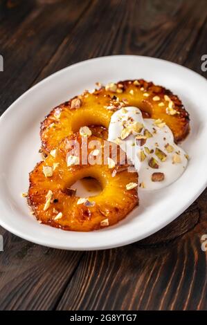 Ananas caramellato con panna montata e pistacchi sul piatto piastra Foto Stock