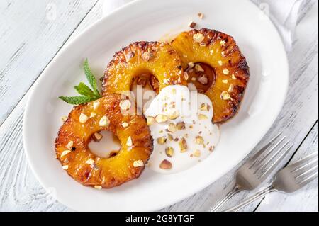 Ananas caramellato con panna montata e pistacchi sul piatto piastra Foto Stock
