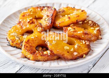 Ananas caramellato con panna montata e pistacchi sul piatto piastra Foto Stock