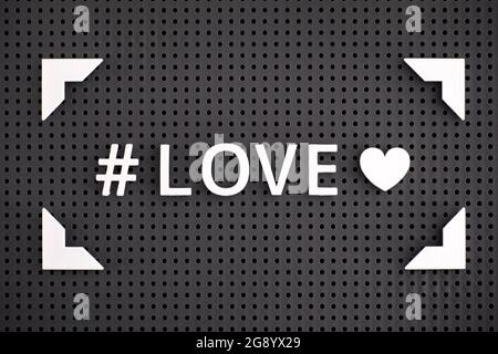 L'hashtag Love with Heart è stato scritto con lettere bianche in una cornice su un tabellone grigio Foto Stock