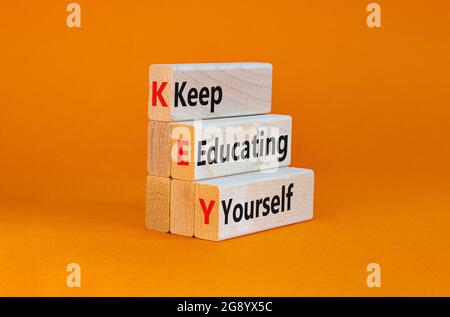 KEY, continuare a educare te stesso simbolo. Blocchi di legno con parole 'CHIAVE, continuare a educare te'. Splendido sfondo arancione, spazio per la copia. Business, educare Foto Stock