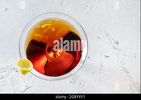Bicchiere di cocktail Martinez guarnito con scorza di limone Foto Stock