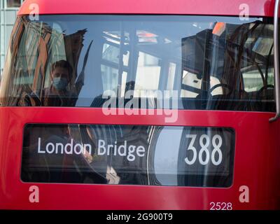 Donna seduta in cima a un autobus a due piani rosso con destinazione London Bridge davanti indossando DPI, maschera per l'uso durante Covid-19, coronavirus, Covid, pandemia Foto Stock