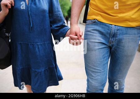 Giovane coppia che tiene le mani mentre cammina insieme al parco Foto Stock