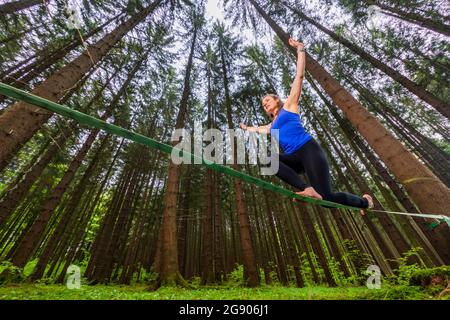 Giovane donna in equilibrio sulla linea di rallentamento nella foresta Foto Stock