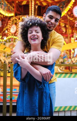 Allegra coppia giovane in piedi con le braccia intorno al parco divertimenti Foto Stock