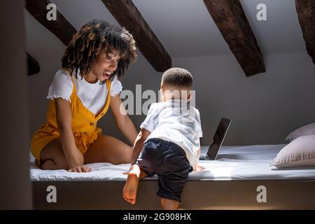 Madre che guarda il figlio che sale a letto a casa Foto Stock