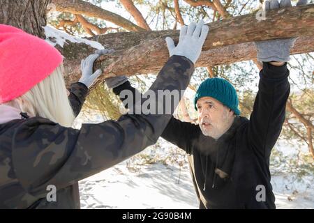Uomo anziano che guarda la donna mentre si appoggia sul ramo dell'albero Foto Stock