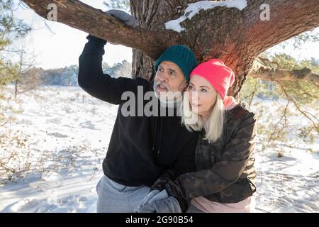 Coppia anziana seduta insieme sotto il ramo d'albero durante l'inverno Foto Stock