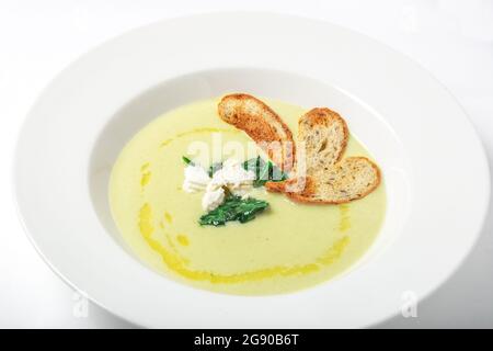 Crema di spinaci minestra con formaggio e crostini in piastra bianca. Foto Stock