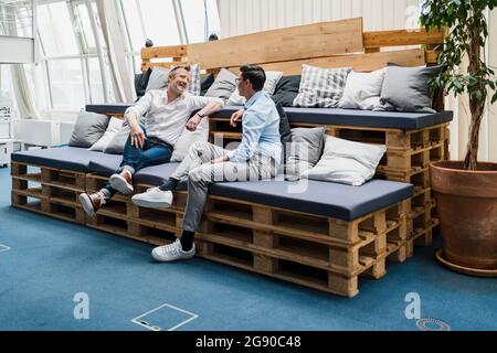 Colleghi di sesso maschile che hanno discusso mentre seduti sul divano in ufficio Foto Stock