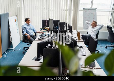 Colleghi di sesso maschile seduti alla scrivania in ufficio Foto Stock