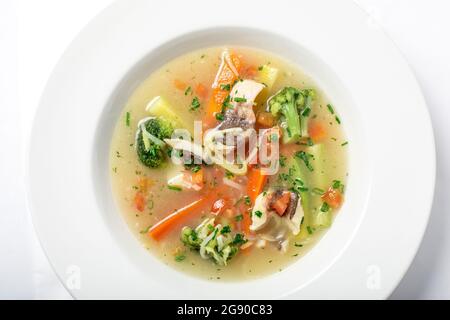 Zuppa di pesce leggera con verdure e broccoli in piatto bianco. Foto Stock