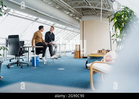 Uomini d'affari che discutono mentre si siedono alla scrivania in ufficio Foto Stock