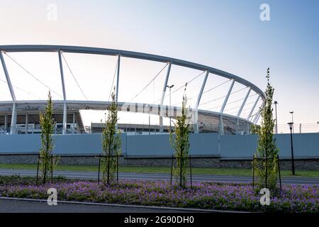 Stadio slesiano visto dall'esterno della recinzione. Campo di fiori viola in primo piano. Serata di sole. Chorzów, Slesia, Polonia. Foto Stock