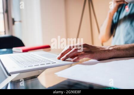 Uomo che usa un notebook mentre lavora a casa Foto Stock