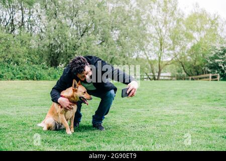 Uomo che prende selfie con cane nel parco Foto Stock