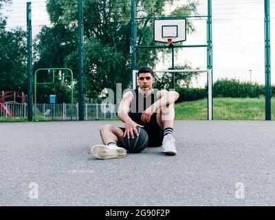 Giocatore di basket seduto con palla sul campo Foto Stock