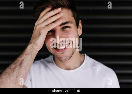 Uomo sorridente con testa in mano davanti all'otturatore nero Foto Stock