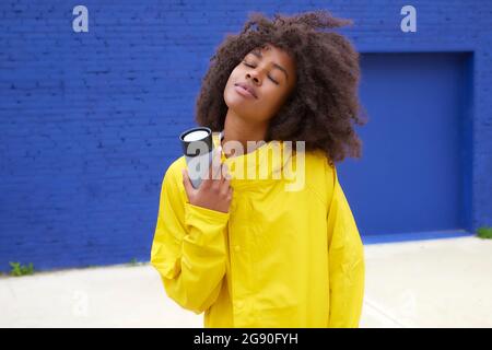 Afrodonna con occhi chiusi che tiene la bottiglia d'acqua Foto Stock