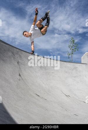 Il giovane uomo che fa acrobazie sopra la rampa di sport in giorno di sole Foto Stock