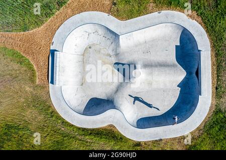 Giovane uomo in pattini in linea che salta sulla rampa sportiva nelle giornate di sole Foto Stock