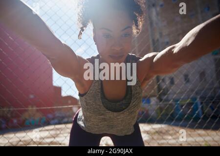 Stretching sportivo mentre si esercita di fronte alla recinzione Foto Stock