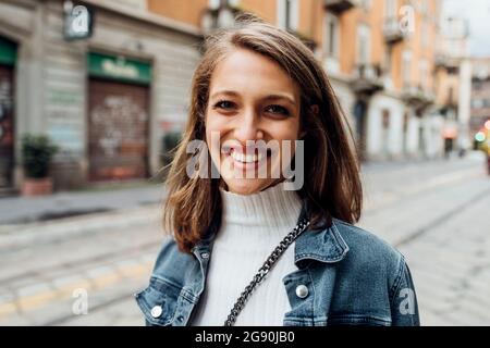 Giovane donna sorridente mentre staring Foto Stock