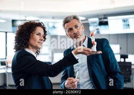 Team professionale che tiene il braccio del robot mentre lavora nell'industria Foto Stock