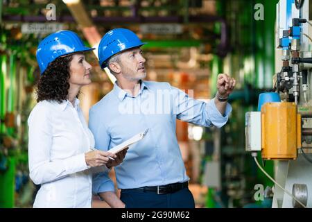 Il team di tecnici controlla la macchina mentre si è in piedi presso la centrale elettrica Foto Stock
