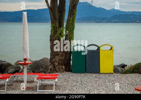 Tre diversi bidoni per la raccolta dei rifiuti per separare la raccolta dei rifiuti sulla riva del lago di Garda Foto Stock