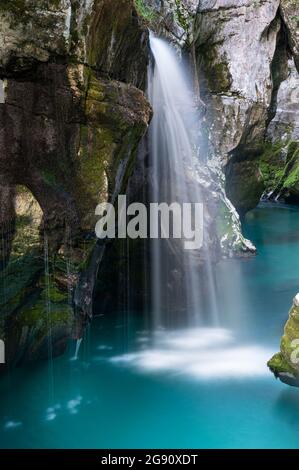 Bel fiume blu di Soca, Slovenia, con una piccola cascata sfocata che scorre tra gole rocciose. Foto Stock
