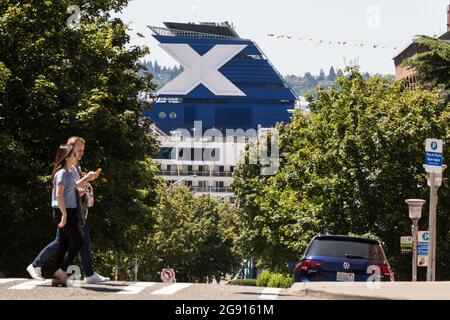 Seattle, Stati Uniti. 23 luglio 2021: Molo 66 a metà giornata una nave da crociera Celebrity X attraccata da Belltown mentre le persone attraversano la strada. Il molo manca di energia a terra, le navi attraccate al molo sono costrette a far funzionare i motori diesel che emettono gas di scarico in città. I residenti del quartiere di Belltown, che corre in parallelo, hanno lamentato un cielo pigro e un aumento significativo dell'inquinamento atmosferico quando le navi da crociera sono attraccate al molo. Il governatore Jay Inslee ha chiesto di ridurre le emissioni di gas serra a livello statale e di investire in energia pulita per affrontare il cambiamento climatico. Credit: James Anderson/Alamy Live News Foto Stock