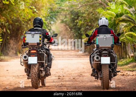 Due uomini che cavalcano la loro moto avventura sulla strada sterrata in Cambogia Foto Stock