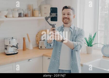 Blog video di registrazione del blogger di giovane uomo con il telefono cellulare a casa Foto Stock