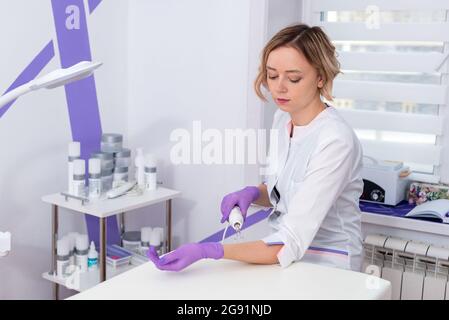 Salone di bellezza. La cosmetologa fa una procedura di peeling dell'acqua per la sua mano. Vista laterale. Il concetto di cura professionale della pelle. Foto Stock