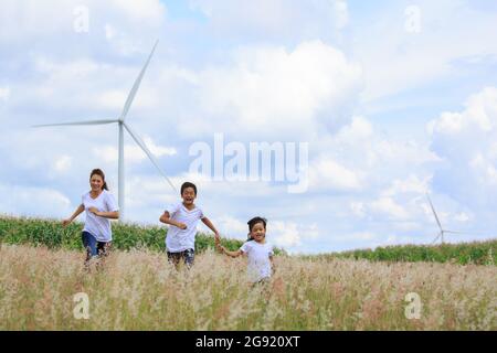 Madre e figlio che giocano in archiviato con enorme turbina eolica in background Foto Stock