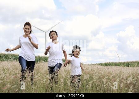 Madre e figlio che giocano in archiviato con enorme turbina eolica in background Foto Stock