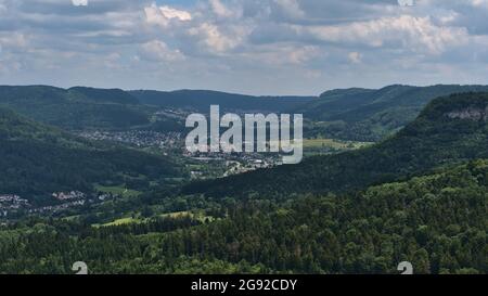 Vista panoramica sulle colline pedemontane dell'Alb sveva dalla scarpata ('Albtrauf') con foreste verdi, villaggio Lautlingen e città di Ebingen, Albstadt, Germania. Foto Stock