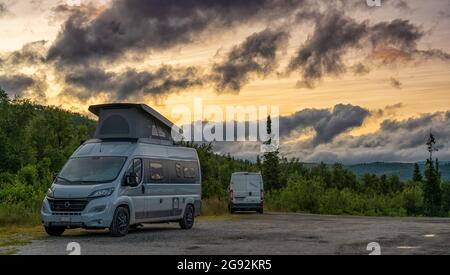 Blasjofallet, Svezia - 10 luglio 2021: Due camper parcheggiati nella natura selvaggia della Svezia settentrionale sotto un colorato cielo di tramonto Foto Stock