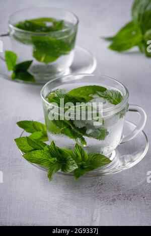 Tè freddo alla menta, bevanda rinfrescante alle erbe in un bicchiere con ghiaccio e foglie fresche su sfondo scuro Foto Stock