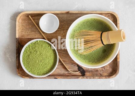 Tè verde Matcha in un vassoio di legno preparazione del tè matcha. Bevanda biologica giapponese tradizionale. Vista dall'alto, disposizione piatta. Foto Stock